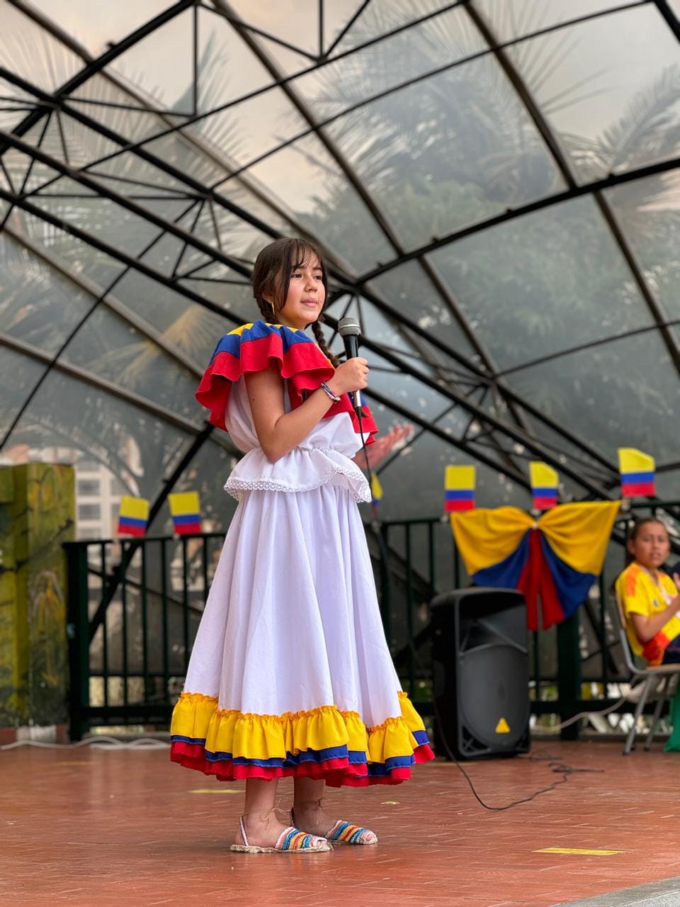 Estudiante de primaria vestida de traje típico y recitando